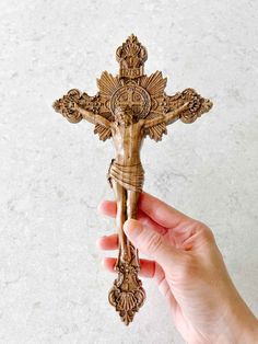 a hand holding an ornate wooden crucifix