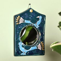 a decorative mirror hanging on the wall next to a potted plant with green leaves