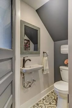 a bathroom with a toilet, sink and mirror in it's corner next to a doorway