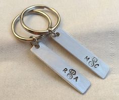 two metal key chains with initials on them