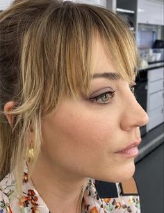 a close up of a person wearing a flowered shirt and gold earrings