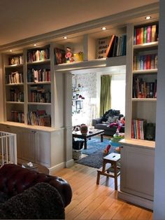 a living room filled with lots of furniture and bookshelves next to a doorway