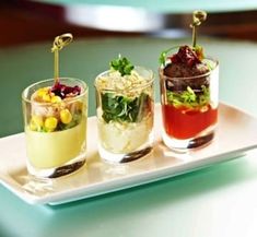 three small glasses filled with different types of food on a tray, sitting on a table