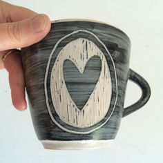 a hand holding a cup with a heart painted on it