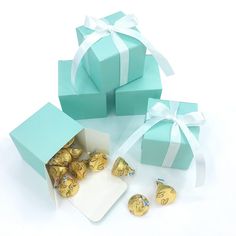 two blue boxes filled with chocolates next to a white ribbon and bow on the top