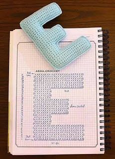 the letter e is made out of crochet and sits on top of a notebook