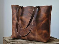 Eye-catching, rustic leather tote bag. Generous size and robust enough for daily use. Limited supply of this wonderful rugged, oiled Spanish pull-up leather: deep brown with amber undertones. Tough and durable; you can see the original texture and marks/scars in the animals skin. When stretched or scratched the colour lightens. If you rub it (or heat it gently) the marks fade. Unlined, natural suede interior. Sturdy brown shoulder straps. Internal canvas zipper pocket for phone/val... Brown Vegetable-tanned Leather Backpack For Daily Use, Leather Shoulder Backpack With Anti-theft Pocket For Everyday Use, Rectangular Leather Backpack With Anti-theft Pocket For Daily Use, Brown Vegetable-tanned Leather Backpack With Adjustable Strap, Louis Vuitton Sarah Wallet, Rectangular Brown Leather Backpack With Anti-theft Pocket, Convertible Bags, Deep Brown, Tote Bag Leather