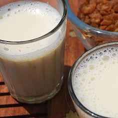 two glasses filled with milk sitting on top of a wooden table