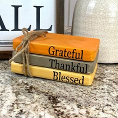 a stack of books sitting on top of a counter next to a white vase and sign