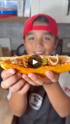 a young boy holding up a piece of food in his hand with the video showing it