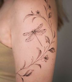 a woman's arm with a dragonfly tattoo on the back of her shoulder