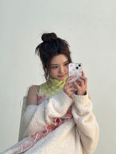 a woman is taking a selfie with her cell phone while wearing a white sweater