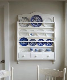 a white china cabinet with blue and white plates on it