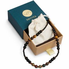 Strength Necklace is made of Blood Stone, Tigers Eye, Onyx, Tibetan Agate. These endurance enhancing gemstones are synergistically combined to achieve your athletic endeavors. Increasing your strength, confidence and focus, this Strength Necklace concentrate your energy into achievements in sports and physical activities. Highly resistant jewelry for various occasions thanks to its strong string material and elaborately selected high quality natural gemstone beads which are unique due to its nature. Hence, uniqueness of gemstones reflect their owners uniqueness. Ideal gift as it comes in a hand tailored pouch protected by a high quality present box. Handcrafted by persevering women who earn their livings through her craftsmanship. Black Sports Jewelry With Round Beads, Strength Necklace, Present Box, Blood Stone, Tigers Eye, Physical Activities, Tiger Eye, Tigers, Gemstone Beads