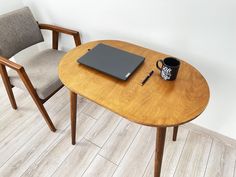 a wooden table topped with a laptop computer next to a chair