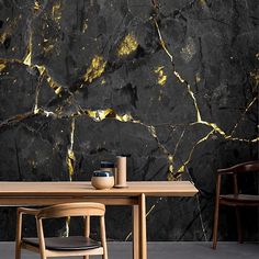 a table with two chairs and a vase on it in front of a black marble wall