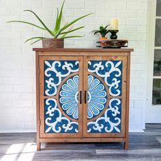 a blue and white cabinet sitting on top of a wooden floor next to a plant