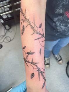 a person with a tattoo on their arm that has branches and leaves all over it