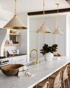 a kitchen with marble counter tops and gold pendant lights