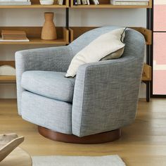 a chair with a pillow on it sitting in front of a book shelf