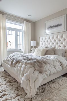 a large white bed sitting in a bedroom next to a window with curtains on the windowsill