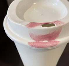 two white vases with pink lipstick on the bottom one has a hole in it