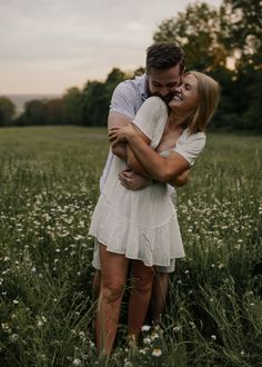 a man and woman hugging in the middle of a field