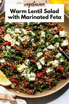 a plate filled with lentils, feta cheese and lemon wedges on top