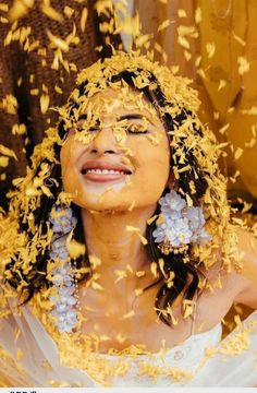 a woman with yellow flowers on her face and hair blowing in the wind as she smiles