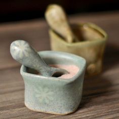 two small ceramic mortars with spoons in them