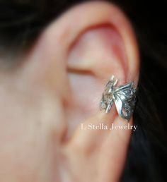 "Ear Cuff- Wide- Non-pierced Lily Flowers delicately carved and joined to wrap around the ear conch area to make a continuous line of flowers in a wide cuff. Lilies are a group of flowering plants which are important in culture and literature in much of the world. I darken, called Oxidize the flowers to enunciate the design. Width- Each flower is 1/2\" wide Diameter is 3/8\" Material- Sterling Silver I do the same design in a single flower for a pierced style. https://www.etsy.com/listing/228197 Silver Clip-on Ear Cuff Gift, Adjustable Silver Ear Cuff As Gift, Adjustable Clip-on Ear Cuff For Gift, Silver Jewelry For Formal Spring Occasions, Silver Formal Jewelry For Spring, Silver Hypoallergenic Ear Cuff For Wedding, Unique Silver Ear Cuff For Wedding, Flower Cuff, Helix Ear