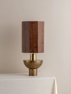 a wooden lamp on top of a white table next to a brown and black lamp shade