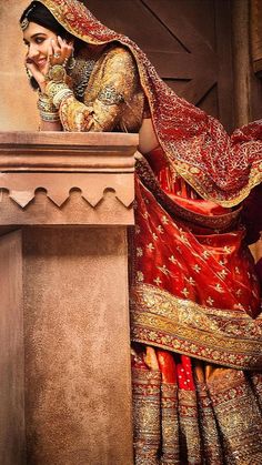 a woman in a red and gold bridal outfit