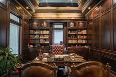 an office with two chairs and a desk in front of a book shelf filled with books