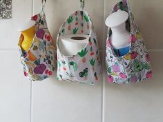 two baby bibs hanging on the wall next to a bottle and toothbrush holder