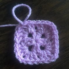 a crocheted square with two holes in the middle