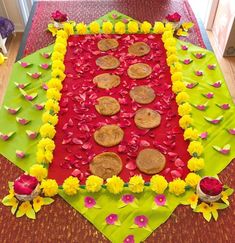 a table topped with lots of cookies and flowers on top of a red cloth covered in paper