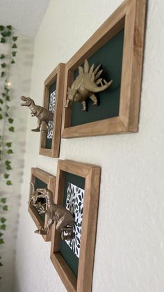 three wooden framed pictures on the wall with metal dinosaurs mounted to it's sides