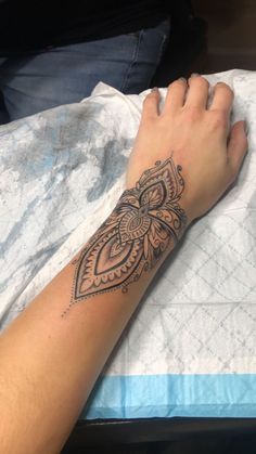 a woman's arm with a tattoo on it and her hand resting on the bed