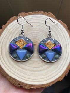 Hand crafted mosaic earrings.  Geometric style with gold foil, iridescent purple/black, and periwinkle glass tiles. Little Jade Gemstones and tiny silver bead accents.  Finished with charcoal gray grout.  Round dangle measures approximately 1 inch long (not including hooks). Earring hooks and setting are made out of hypoallergenic stainless steal. Unique Iridescent Pierced Earrings, Unique Iridescent Earrings, Bohemian Iridescent Dangle Earrings, Bohemian Iridescent Earrings With Ear Wire, Handmade Iridescent Metal Earrings, Iridescent Metal Drop Earrings, Iridescent Bohemian Earrings As Gift, Iridescent Bohemian Earrings For Gifts, Unique Multicolor Geometric Jewelry