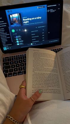 a person laying in bed with an open book next to a laptop computer and keyboard