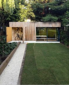 an outdoor area with green grass, gravel and wooden structure on the side of it