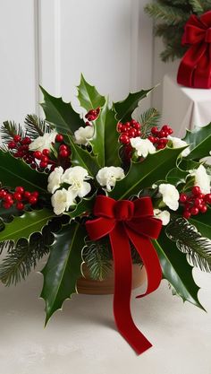 a christmas arrangement with holly, white flowers and red berries