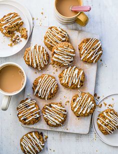 iced cookies with icing on a cutting board next to two cups of coffee