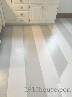 a kitchen with white cabinets and striped flooring