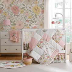 a white crib with pink and yellow flowers on the wall next to a window