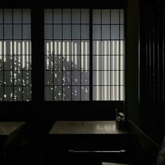 two windows in a dark room with blinds on them