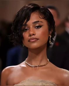 a close up of a woman wearing a necklace and earrings on her head with people in the background