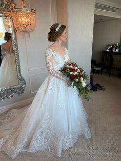 a woman in a wedding dress is looking at herself in the mirror and holding a bouquet