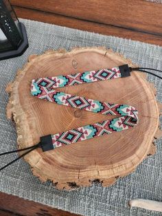 two colorful beaded bracelets sitting on top of a piece of wood next to an electronic device